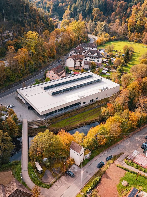 Modern sports hall in the midst of an autumn landscape with colorful trees and a small river, Walter Lindner Sporthalle Calw, Black Forest, Germany