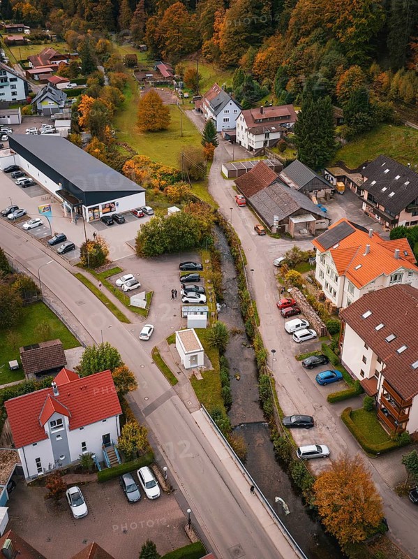 Aerial view of a small village in autumn with colorful trees, roads, buildings and a small river, Calmbach, Bad Wildbad, Black Forest, Germany