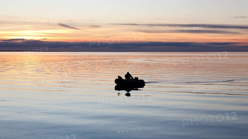 An angler docks on the shore with his inflatable boat and dog, Fehmarn Island, 18.10.2025, Fehmarn, Schleswig-Holstein, Germany