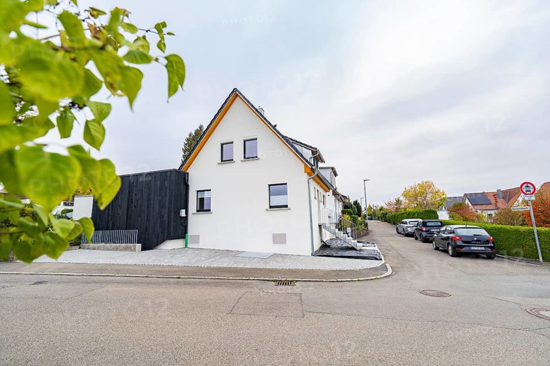 Side view of a bright residential building in a quiet settlement with parked cars and hedges, house renovation, climate renovation, Metzingen, Germany
