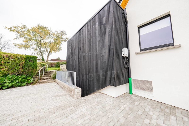 Modern house side with black wood paneling on paved driveway, house renovation, air conditioning renovation, Metzingen, Germany