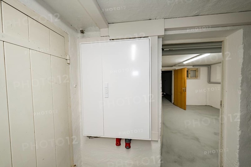 Simple basement corridor with white electrical distributor on plastered wall, objectively illuminated, access to other adjoining rooms, house renovation, air conditioning renovation, Metzingen, Germany