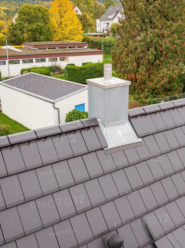 Fireplace with metal cladding on anthracite-colored roof, view over the residential area, house renovation, climate renovation, Metzingen, Germany
