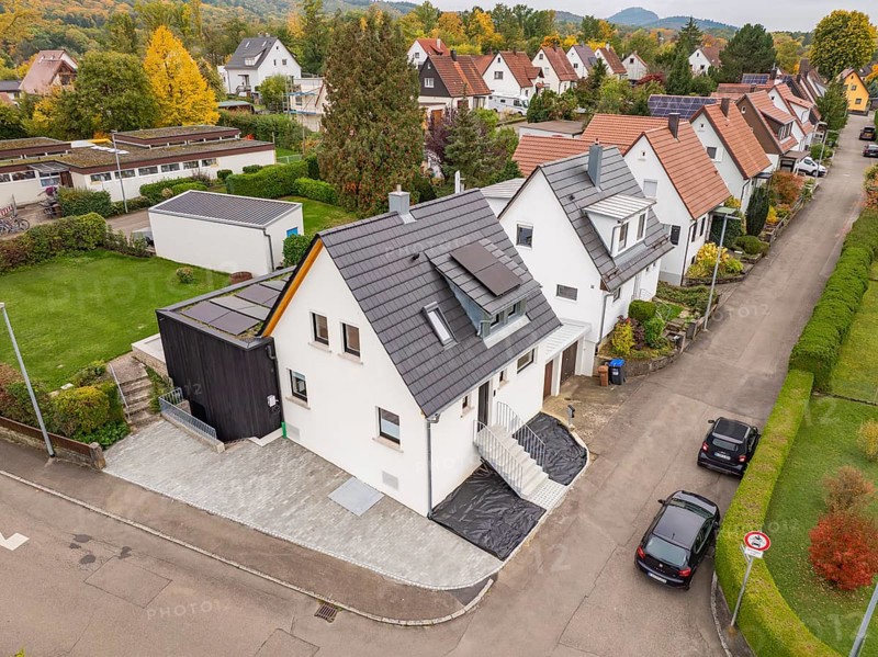 Aerial view of a quiet residential street with modernized house and extension, nestled in autumn gardens, house renovation, climate renovation, Metzingen, Germany