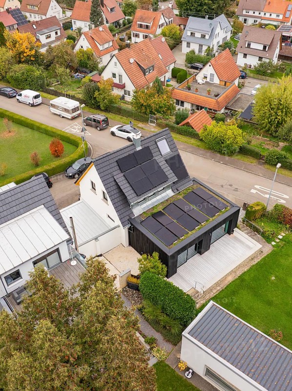 Top view shows PV modules and covered terrace at a modern extension with large wooden deck and garden, house renovation, climate renovation, Metzingen, Germany