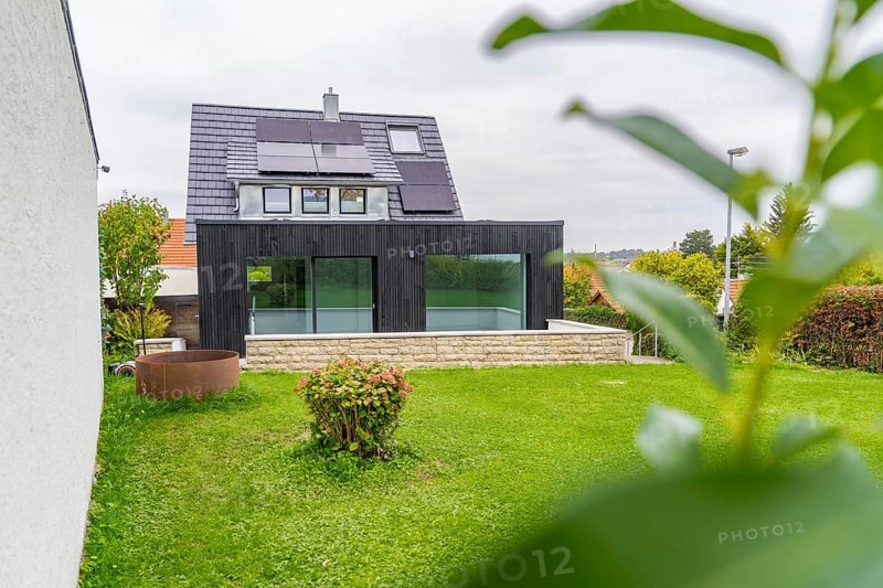 Modern extension with glass front on a green garden, framed by leaves in the foreground, quiet atmosphere, house renovation, air conditioning renovation, Metzingen, Germany