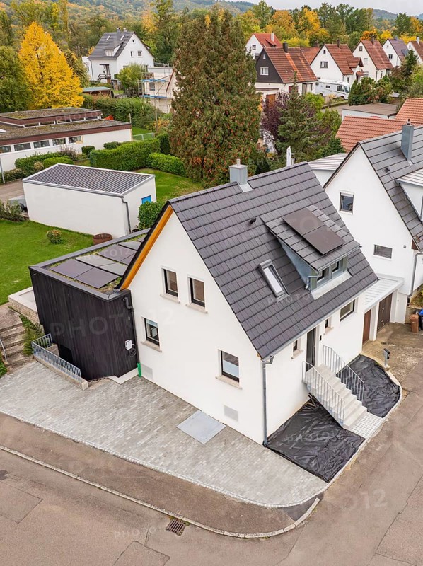 Drone view of a single-family house with modern extension and solar panels in a quiet settlement in an autumnal atmosphere, house renovation, climate renovation, Metzingen, Germany