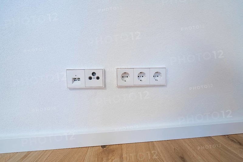 Modern sockets and connections neatly integrated into a white wall over oak floors, house renovation, climate renovation, Metzingen, Germany