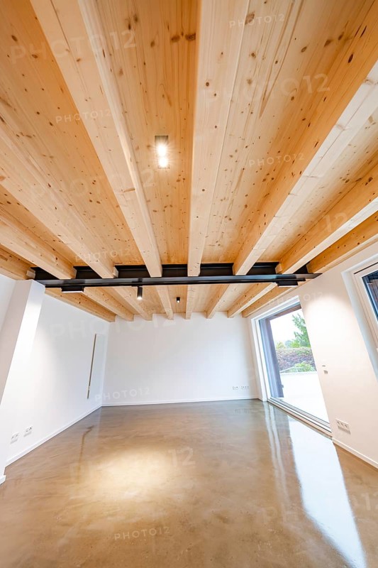 Living area with solid wooden ceiling and black steel beams over polished concrete floor, lots of daylight, house renovation, air-conditioning renovation, Metzingen, Germany