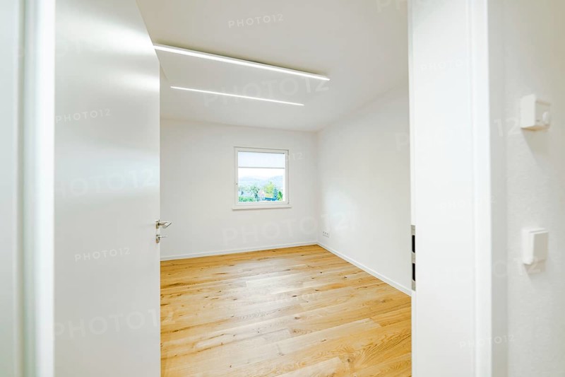 Empty, bright room with oak floor, white door and window, modern linear lights on the ceiling, house renovation, air conditioning renovation, Metzingen, Germany