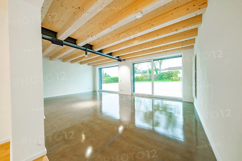 Large, bright living room with exposed wooden beams, polished concrete floor and large sliding doors to the garden, house renovation, air conditioning renovation, Metzingen, Germany