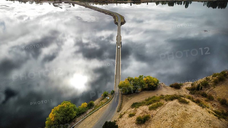 A long bridge over a shallow and calm lake on a cloudy day, photographed with a drone