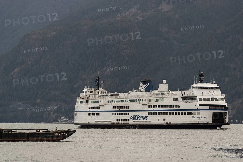 Ferry navigating across water with towering mountains under overcast skies in Horseshoe Bay, West Vancouver, British Columbia, Canada