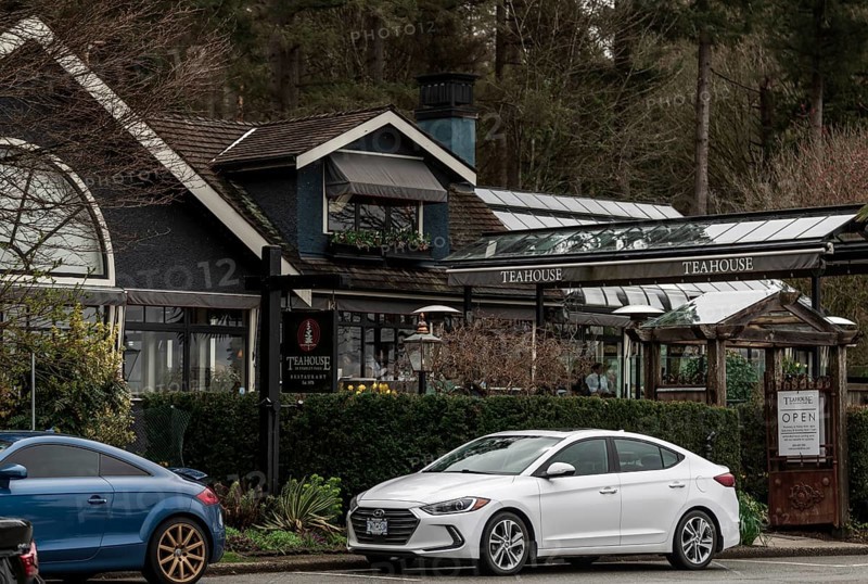 A teahouse in Stanley Park with parked cars, surrounded by lush greenery and overcast skies in Vancouver, British Columbia, Canada