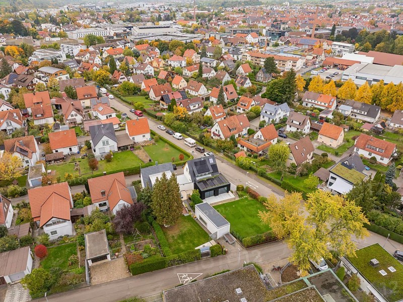 Autumn settlement with yellow tree avenue and view of the city under grey clouds, Metzingen, Germany
