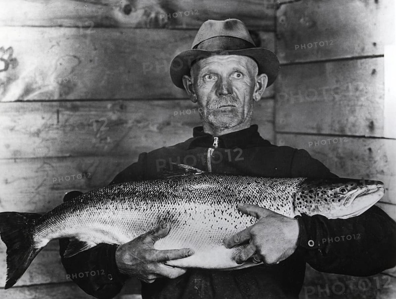 Fisherman with large salmon, presumably a king salmon or quinnat (Oncorhynchus tshawytscha), ca. 1930, USA