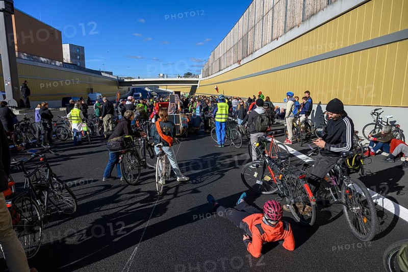 Cyclists wait to continue their journey. Meanwhile, a woman wearing a helmet is lying on the asphalt and resting. Bicycle demo on the recently inaugurated 16th construction phase of the A100, Berlin, 18.10.2025