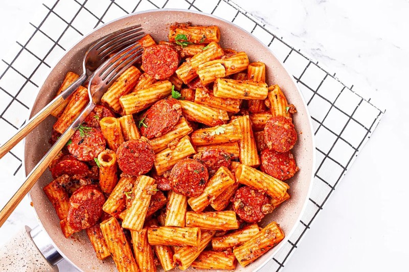 Rigatoni pasta with spicy sausage, and rich tomato sauce served, on a white plate, homemade