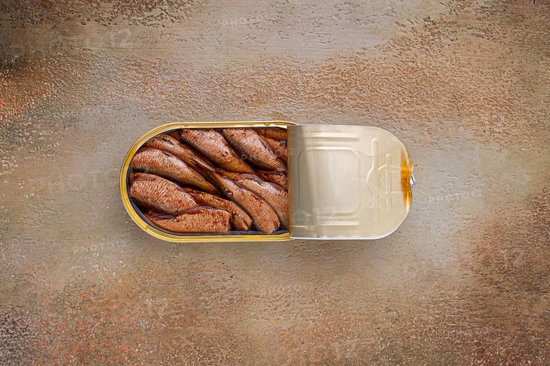 Open tin can with sprats, appetizer, on the table, top view
