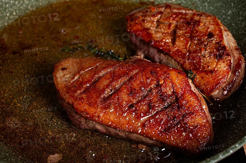Cooking duck breast, in a frying pan, fried, with spices and herbs, close-up, no people