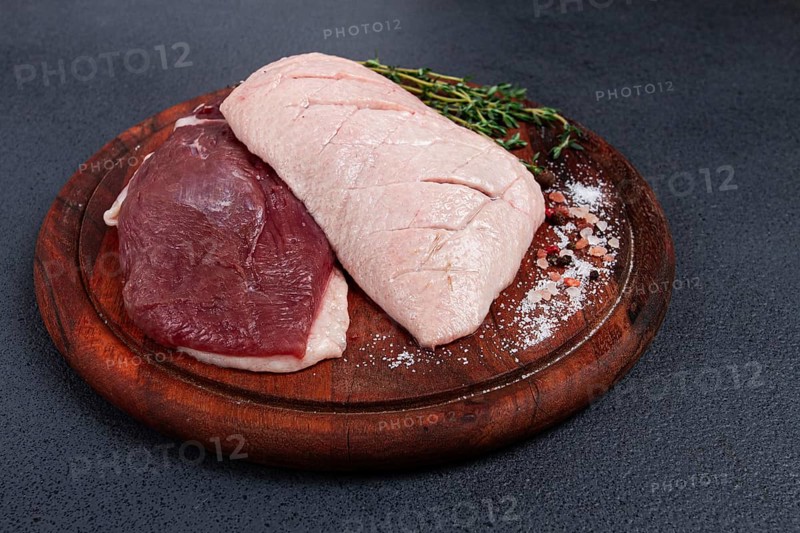 Fresh raw duck breasts, on a wooden chopping board, with herbs and spices, no people