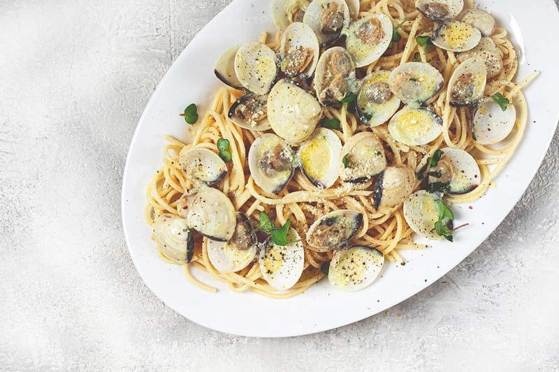Spaghetti with vongole clams, in cream sauce, carbonara, on a white plate, homemade, top view, no people