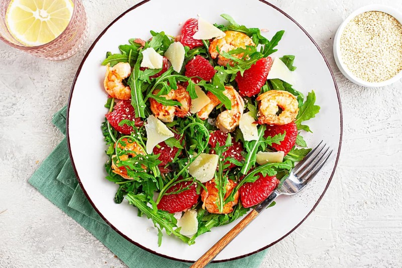 Fresh shrimp salad with arugula, grapefruit, and parmesan served in a bowl