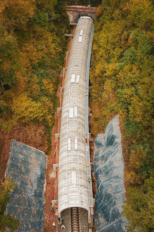 Aerial view of a long tunnel on a railway line surrounded by autumn leaves, Hermann-Hesse-Bahn construction site, Calw, Germany