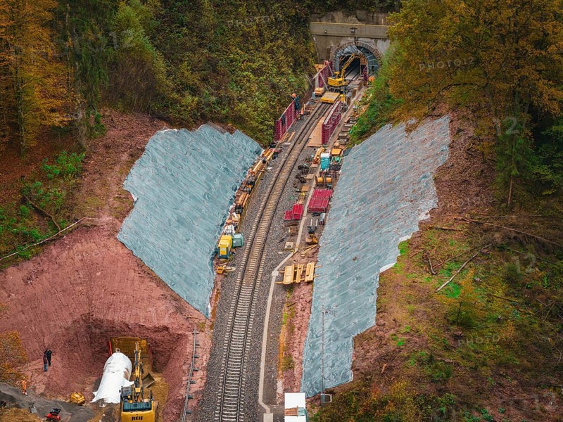 Working at the tunnel entrance to a railway line, with construction equipment and soil in an autumn environment, Hermann-Hesse-Bahn construction site, Calw, Germany