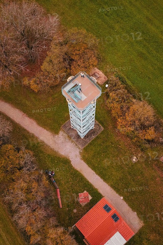Aerial view of a tower surrounded by trees and paths in autumn colors and green fields, Dürrenmettstetten observation tower, Germany