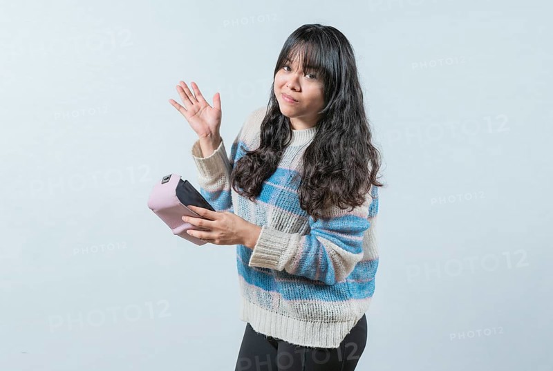 Worried girl with no money holding empty wallet, isolated. Young woman shaking her empty wallet