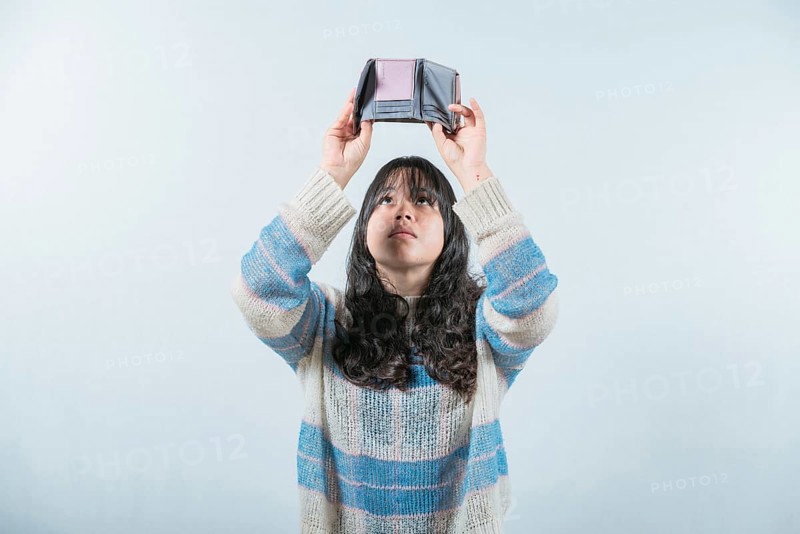 Young woman shaking her empty wallet. Worried girl with no money holding empty wallet, isolated