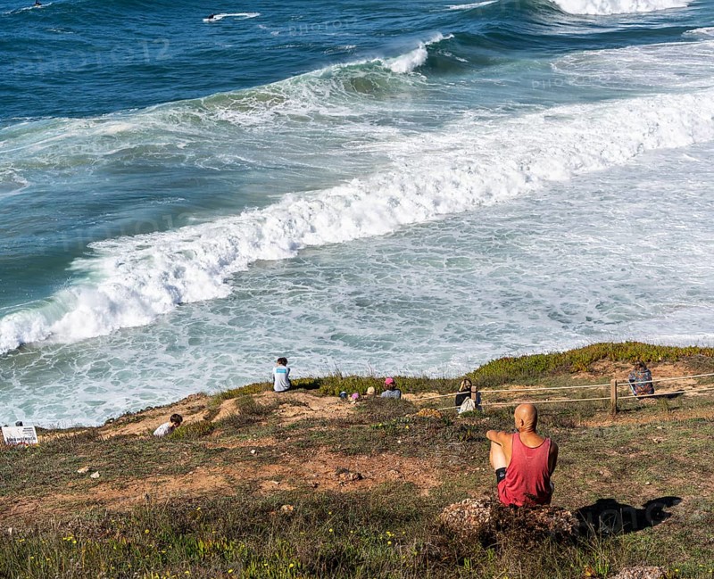 Tourists watch the waves of the Atlantic on the rocky plateau of Sito, also known as Forte São Miguel, a surfing paradise with monster waves in the months of November to February, Nazaré, Portugal