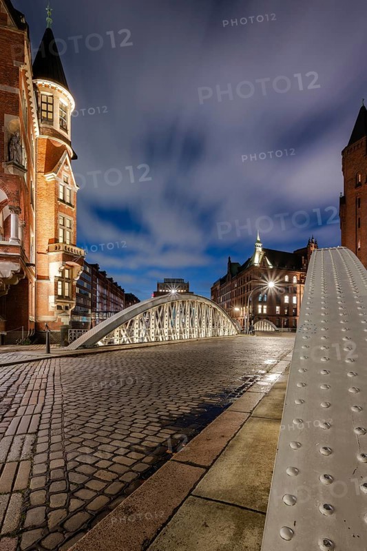 Blue hour in the Speicherstadt Hamburg on the Neuerwegsbrücke with cobblestones in the foreground and moving clouds in the background, Hamburg, Germany