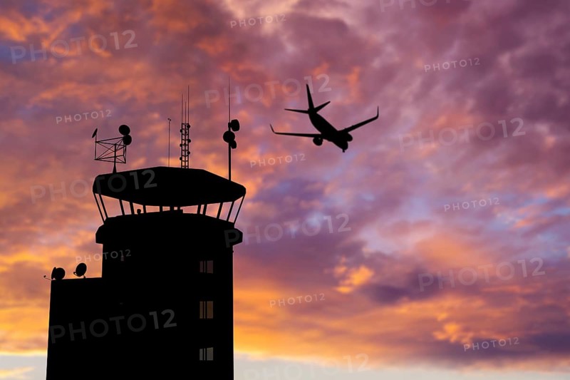 Air traffic control tower at airport as airplane takes off