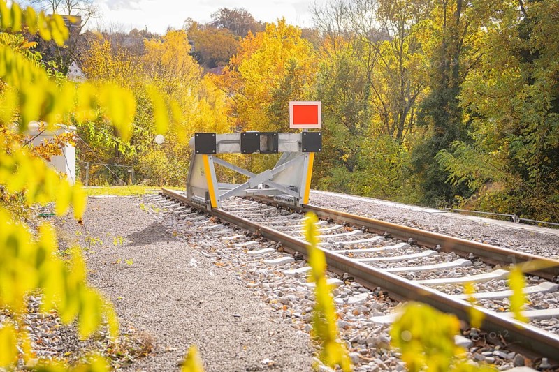 Railway track ends with a barrier surrounded by autumnal nature, ZOB Calw, Hermann Hessebahn, Calw, Germany