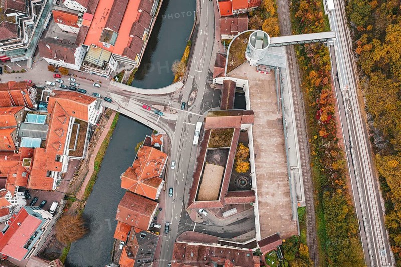 Aerial view of a city with a river and bridges, surrounded by autumn-colored trees, ZOB Calw, Hermann Hessebahn, Calw, Germany