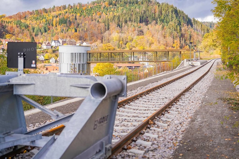 Tracks along a modern building with a bridge against an autumn mountain backdrop, ZOB Calw, Hermann Hessebahn, Calw, Germany