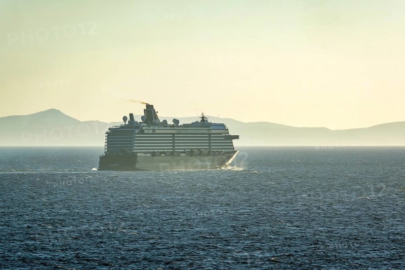Mykonos, Cyclades, Greece - Cruise ship MEIN SCHIFF 5 sails out of Mykonos harbour bay and leaves behind a dark exhaust cloud