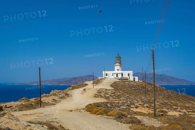 Mykonos, Cyclades, Greece - The Armenistis lighthouse in the north of the island is a landmark and a popular destination for tourists. In the back is the island of Tinos
