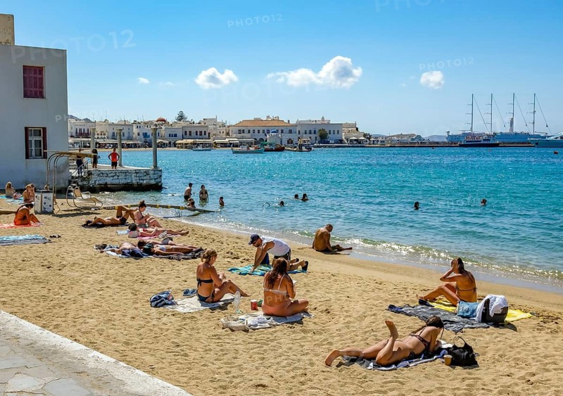Mykonos, Cyclades, Greece - Tourists and locals like to bathe at the small town beach Paralia Cheras Mikonou right at the old port in the old town of Mykonos Town, Mykonos Chora. Mykonos is part of the Cyclades archipelago