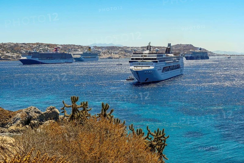 Mykonos, Cyclades, Greece - cruise ships CARNIVAL MIRACLE, COSTA FORTUNA, MEIN SCHIFF 5 and MSC LIRICA are located in the bay off Mykonos Town. Old town with windmills. Cruise ships bring tourists to shore