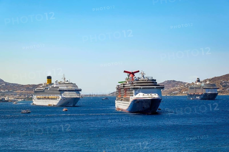 Mykonos, Cyclades, Greece - cruise ships CARNIVAL MIRACLE, COSTA FORTUNA and MEIN SCHIFF 5 are located in the bay off Mykonos Town with a view of the old town with the windmills. Cruise ships bring tourists to shore