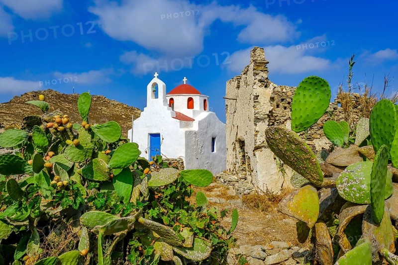 Ano Mera, Mykonos, Cyclades, Greece - Small church from the 18th century on the site of the Gyzi ruins, 13th century castle ruins by the Venetian Gyzi family, right next to the Paleokastro monastery in the interior of the island just outside Ano Mera, is now a tourist attraction much visited by tourists. Typical fig cacti in front