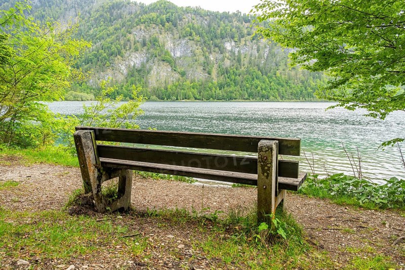 Park bench standing beside beside and with view onto Lake Offensee on a cloudy day in spring, Salzkammergut, Austria