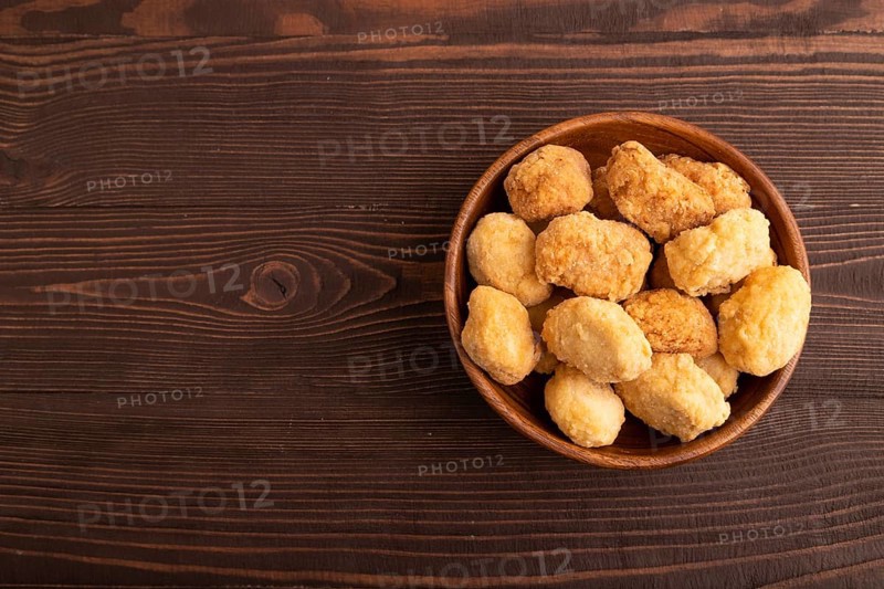Fried crispy Chicken Nuggets on brown wooden background. top view, flat lay, copy space