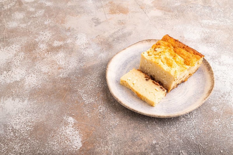?ottage cheese ?asserole, Curd cake, with dried apricots and raisins on brown concrete background, side view, copy space, minimalism