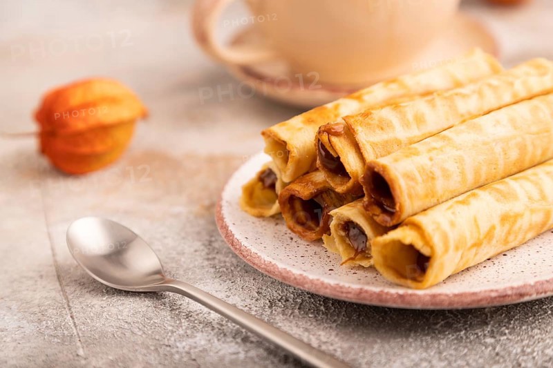 Waffles with caramel on brown concrete background and orange linen textile, cup of coffee, side view, close up, selective focus
