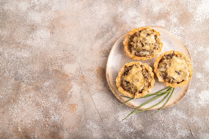Tartlets with meat and cheese on brown concrete background. top view, flat lay, copy space