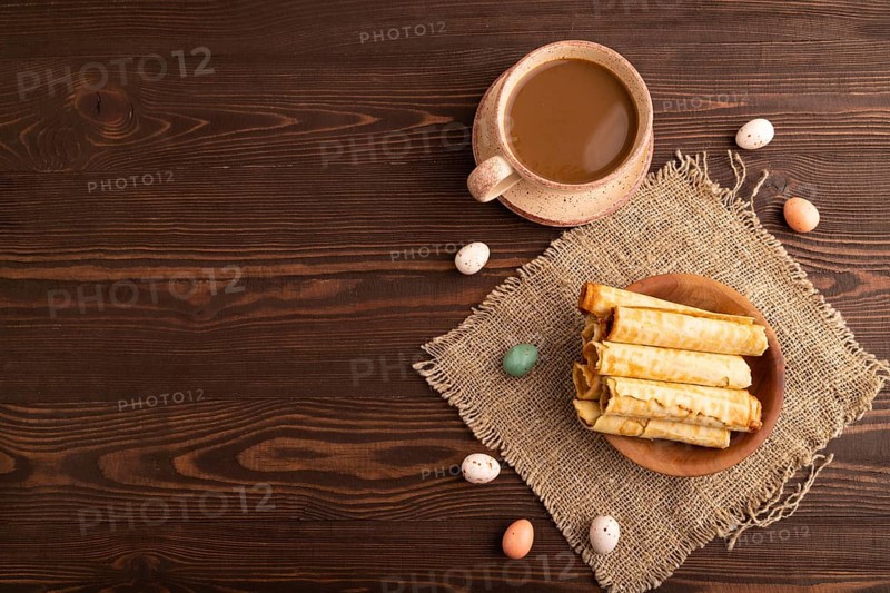 Waffles with caramel on brown wooden background and linen textile, cup of coffee, top view, flat lay, copy space